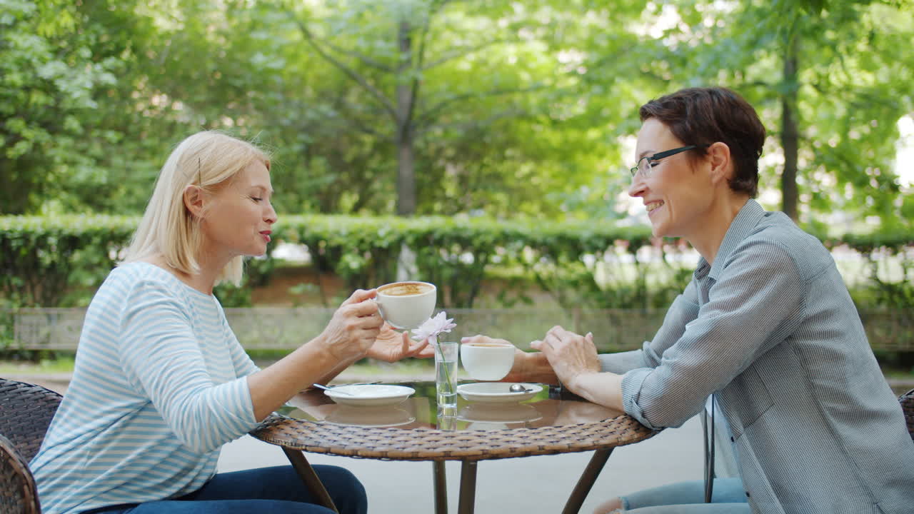 두 명의 여성이 야외에서 커피를 즐기고 있습니다.