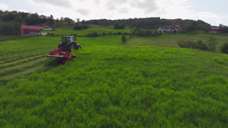 Drone-tracking-shot-of-tractor-with-mower-conditioner-harvesting-lush-field-crop