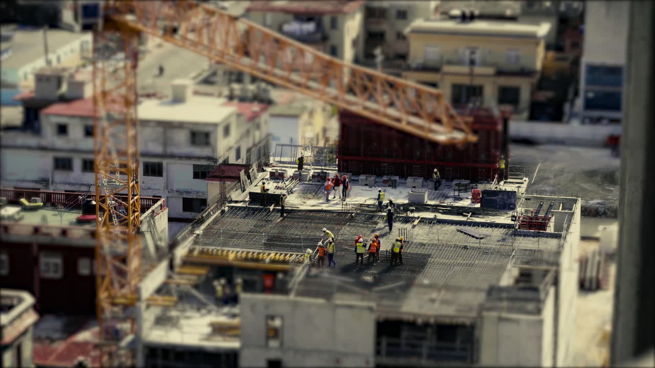 Construction workers wearing high visual clothing and laying steel reinforcement preparing for the concrete to be poured. Tilt and shift, stop motion, miniature world.