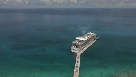 High-aerial-approaches-massive-Caribbean-cruiseship-at-Coco-Cay-pier