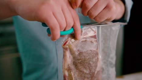 Close-up-view-of-a-man-cutting-the-steak-packed-polythene-wrap-with-a-pair-of-scissors