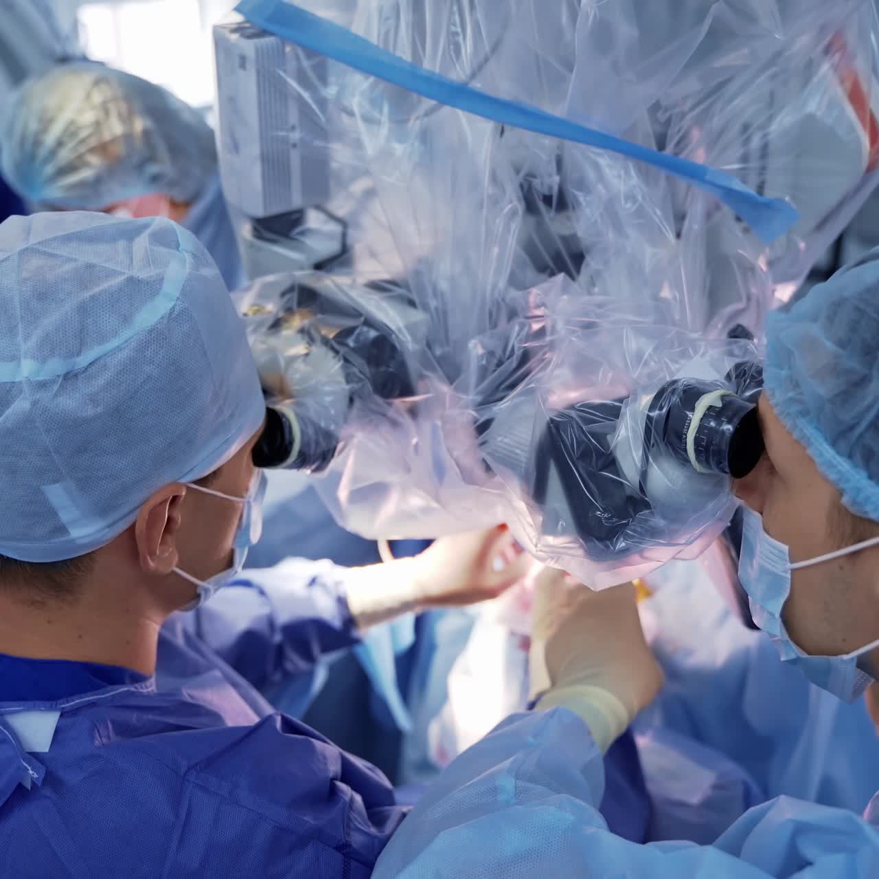 Teamwork of doctors in the operating room. Surgeons use medical microscope during operation to a patient in the hospital. Top view.
