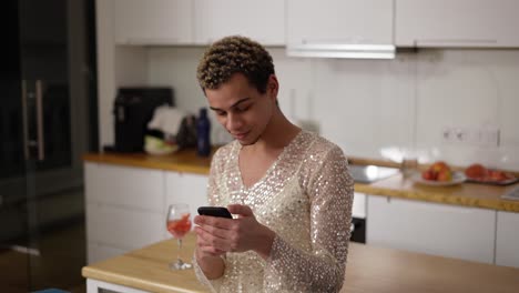 cheerful guy in fancy dress using mobile phone at home kitchen