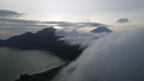 white clouds moving over the silhouettes of mount batur during sunrise