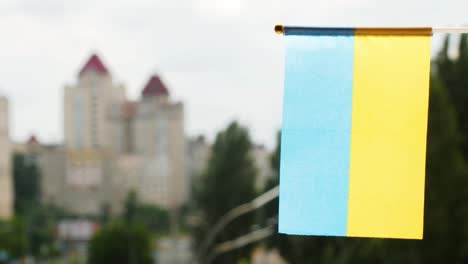 vertikal die flagge der ukraine gegen den blauen himmel und die stadtstraße gesetzt, mit platz für den text. blau-gelbe ukraine-flagge. ukrainische flagge schwenken. die feiertagsflagge der ukraine auf der sonne