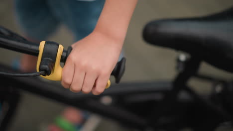 a close-up of a little boy's hand firmly gripping the brake lever of a bicycle, and resting his hand on the handlebar