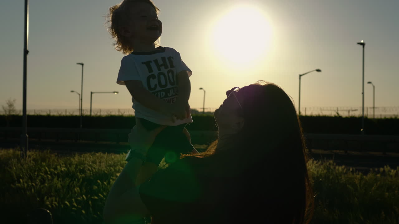 Close up of mom and son having fun and giggling in beautiful, soft sunset light