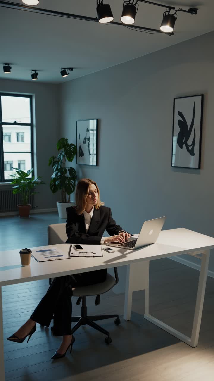 Donna professionista in un ambiente d'ufficio moderno, che lavora al portatile