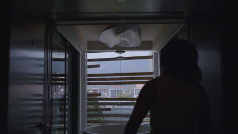 Tilting-silhouette-shot-of-a-woman-entering-a-hotel-room-with-an-open-plan-bathroom