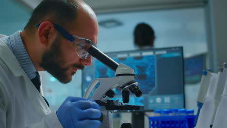 Lab-technician-examining-samples-and-liquid-using-microscope