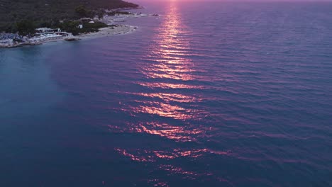 Mediterranean-sunset-over-scenic-Ksamil-coastline,-drone-tilt-up