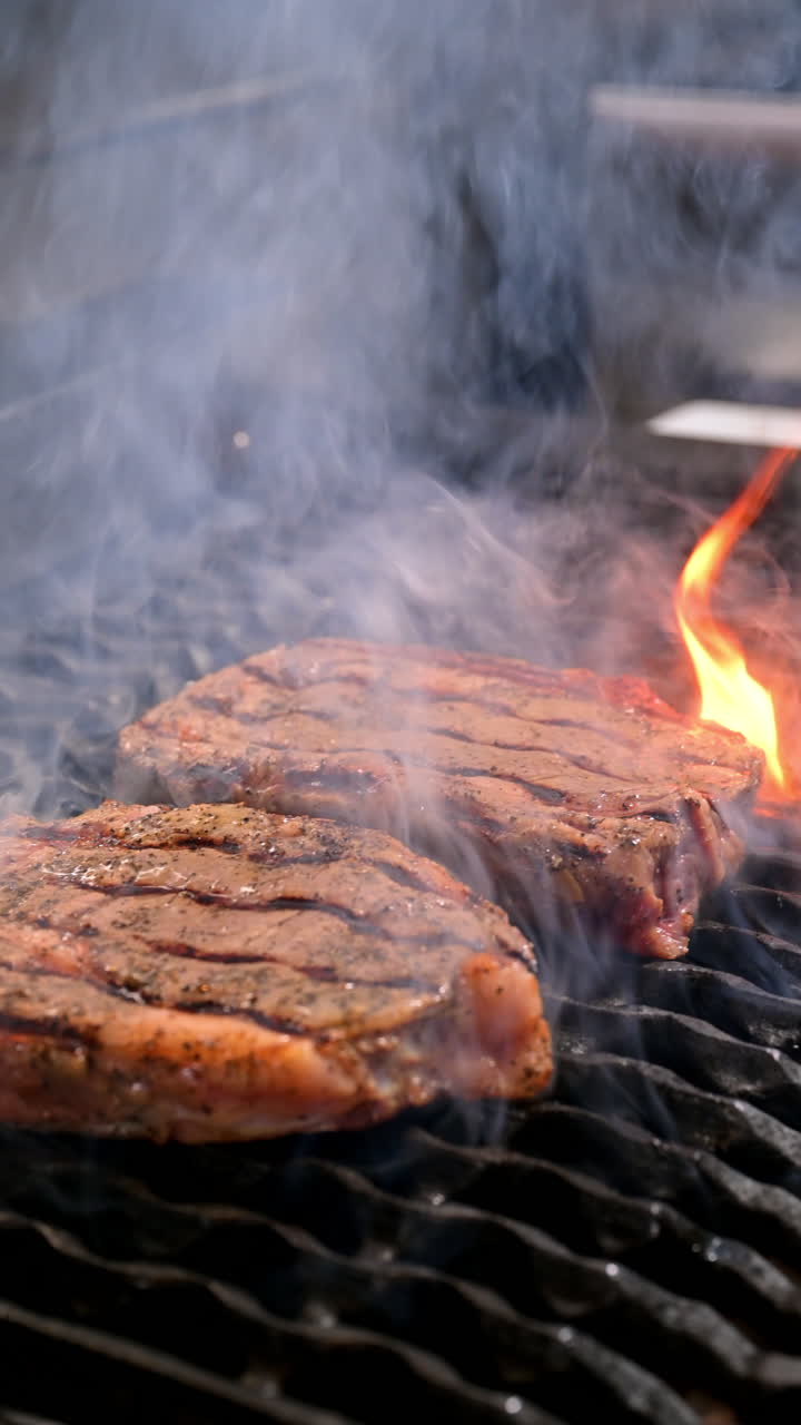 Chef seasons grilled steak with rosemary. Close-up of chef seasoning grilled steak on the barbecue with fresh rosemary