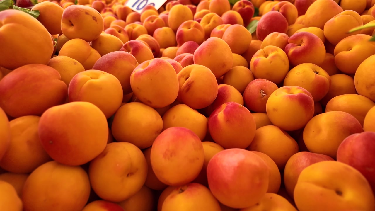 Vibrant Display of Fresh Apricots and Strawberries at a Fruit Market