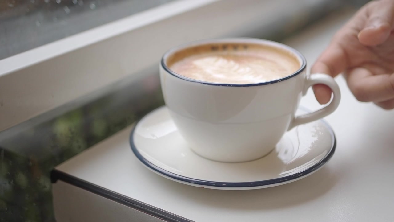 Una mano che prende una tazza di caffè da un piattino