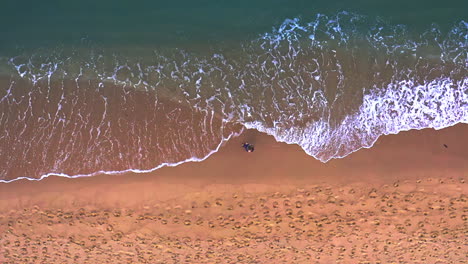 woman walking on tropical beach washed by foamy ocean waves, thailand