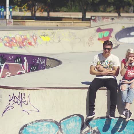 young couple sitting on a wall at a skate park