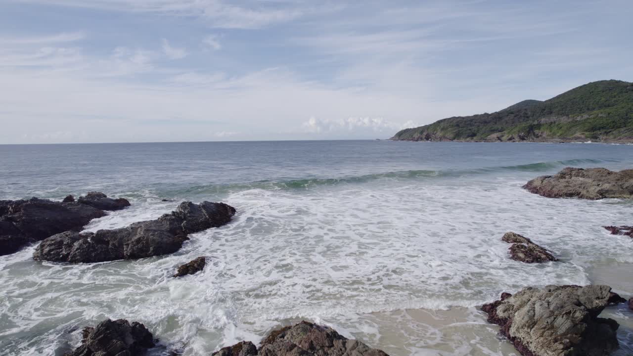 คลื่นทะเลมีฟองบนชายฝั่งหินของหาดเบอร์เจสในฟอร์สเตอร์ ออสเตรเลีย - ภาพถ่ายทางอากาศจากโดรน