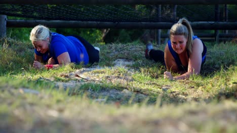 mujeres decididas arrastrándose bajo la red durante una carrera de obstáculos