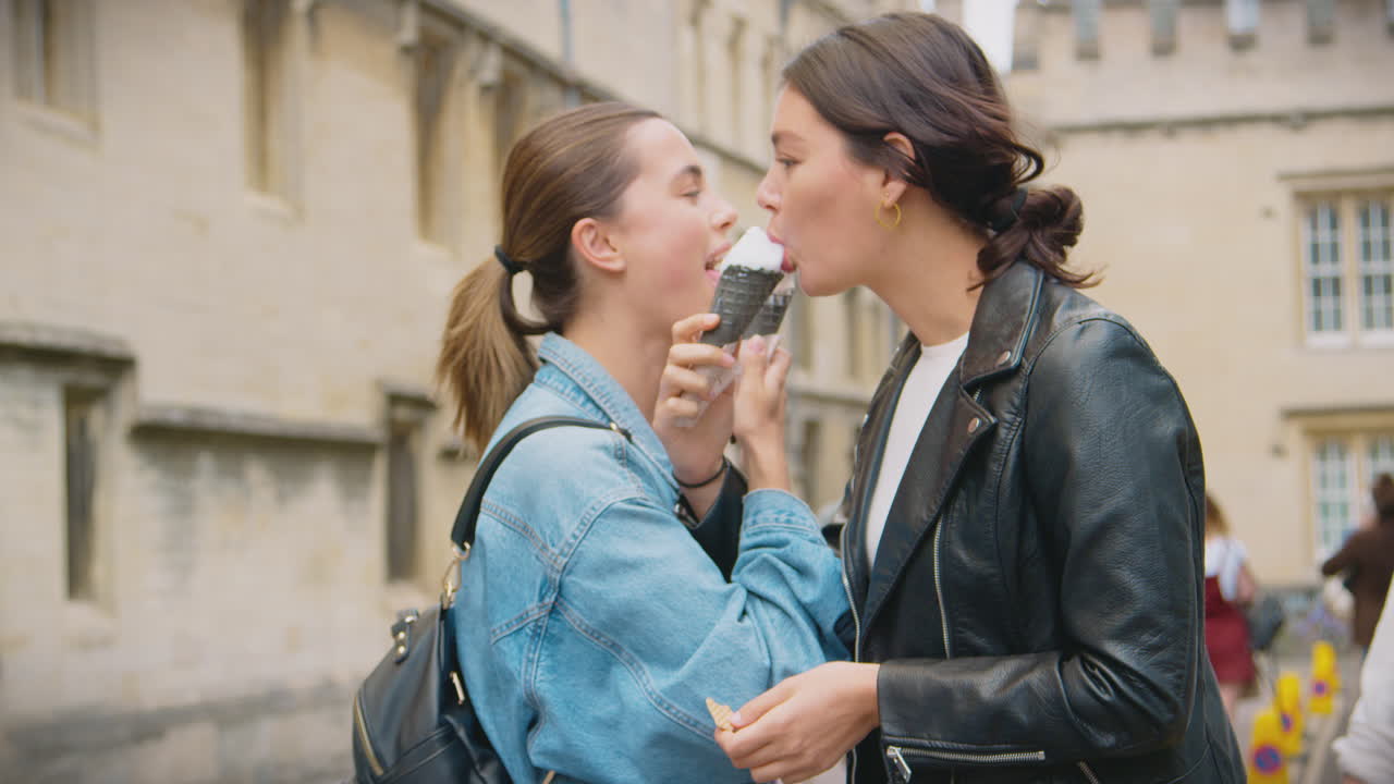 Coppia di donne che visita i luoghi e mangia gelati mentre passeggiano insieme per Oxford, Regno Unito.