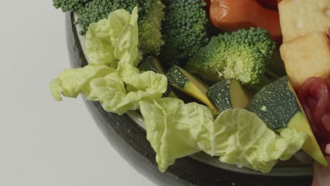 close up of a pot of shabu ingredients spinning around on white table in the kitchen