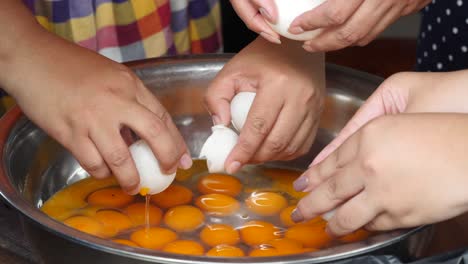 close up of hands separate egg yolks from egg whites in thai dessert recipes.