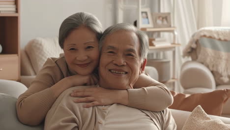 happy elderly asian couple embracing at home