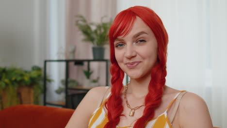 Close-up-of-happy-beautiful-teenager-redhead-ginger-woman-smiling-looking-at-camera-at-home-on-couch