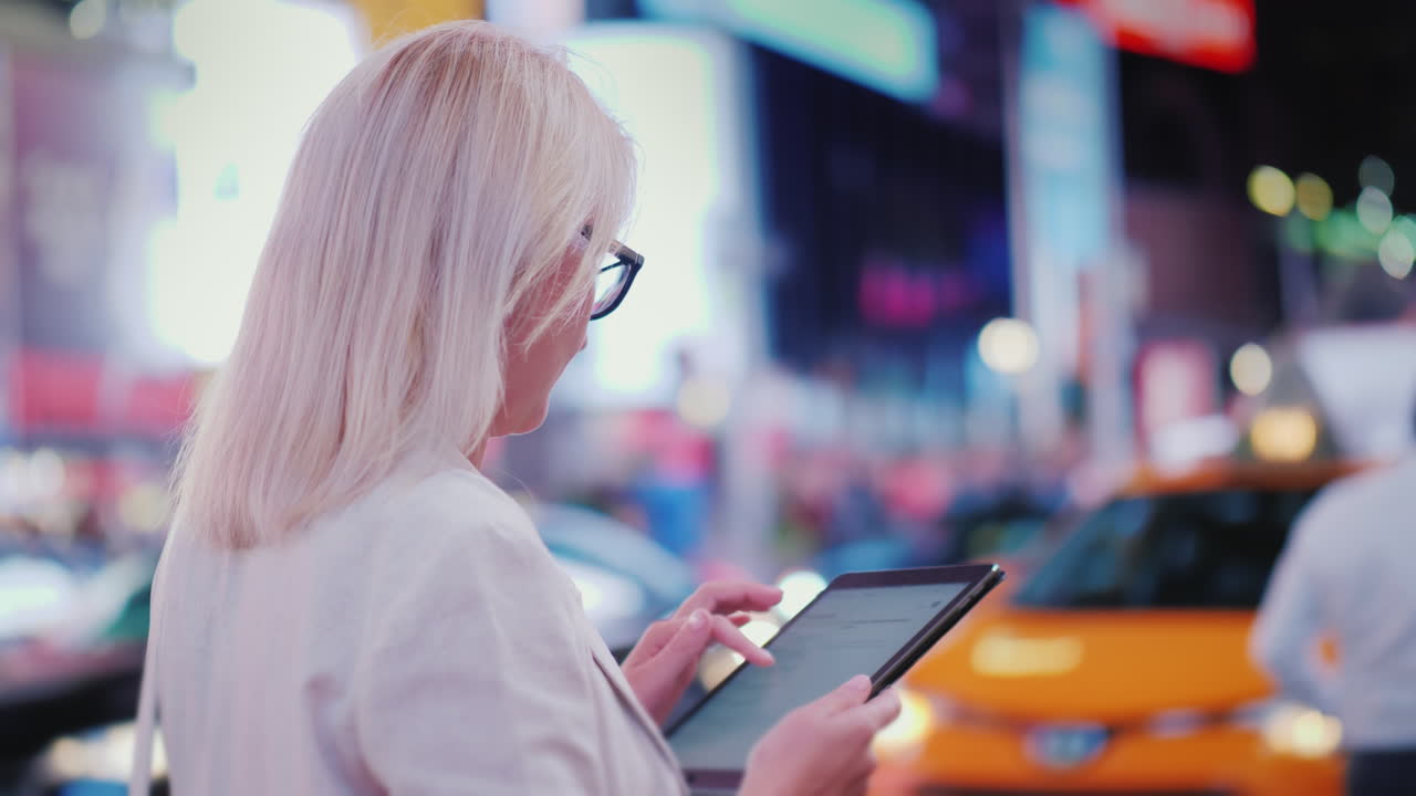 mujer de negocios usa una tableta en la concurrida times square en nueva york, los famosos taxis amarillos están pasando