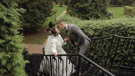 Newlyweds,-caucasian-groom-with-bride-stay-on-stairs-in-park,-wedding-couple,-man-and-woman-in-love