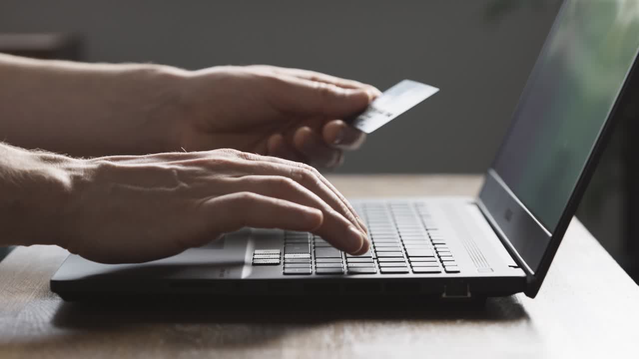 мужчина оплачивает покупки в интернет-магазине с помощью кредитной карты и ноутбука