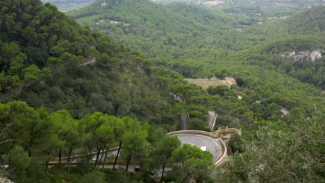 Coches-Circulando-Por-Una-Carretera-Con-Curvas-En-Las-Montañas,-Parcialmente-Cubiertas-Por-árboles