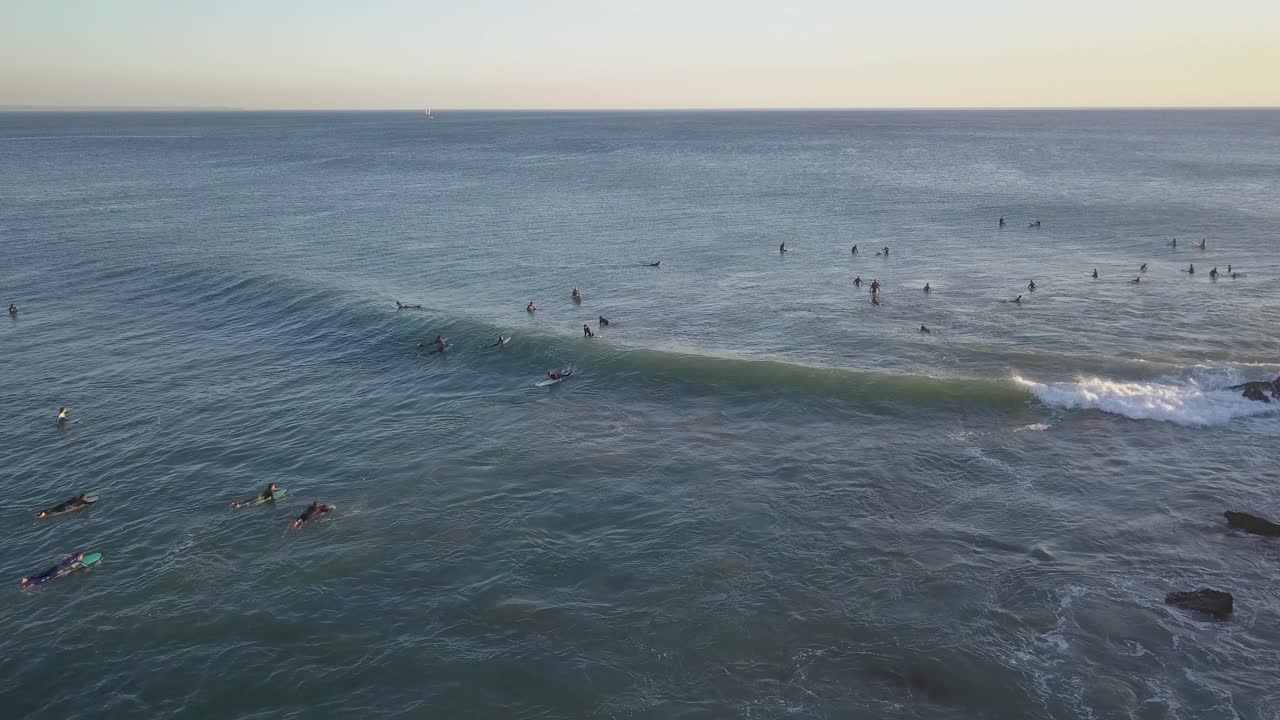 Ilmavideo surffaajista liikkeessä auringonlaskun aikaan Atlantin valtamerellä Costa da Caparicassa, Lissabonissa, Portugalissa.