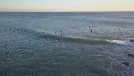 video aéreo de surfistas en movimiento durante la puesta de sol en el océano atlántico en costa da caparica, lisboa, portugal