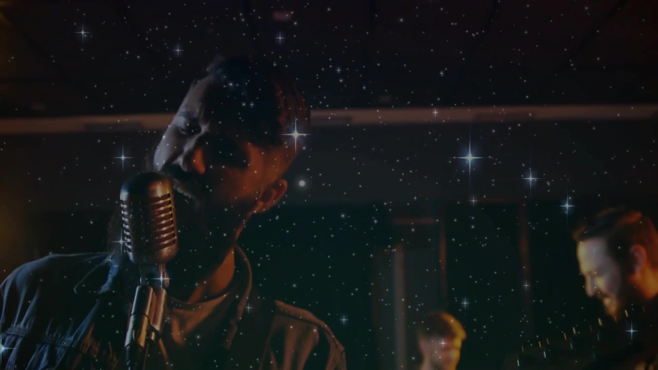Vertical video: Singer leaning into vintage mic, driving guitar for chorus under star overlay