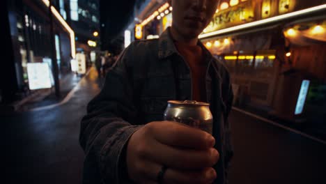 young man enjoying a soda in a japanese city at night