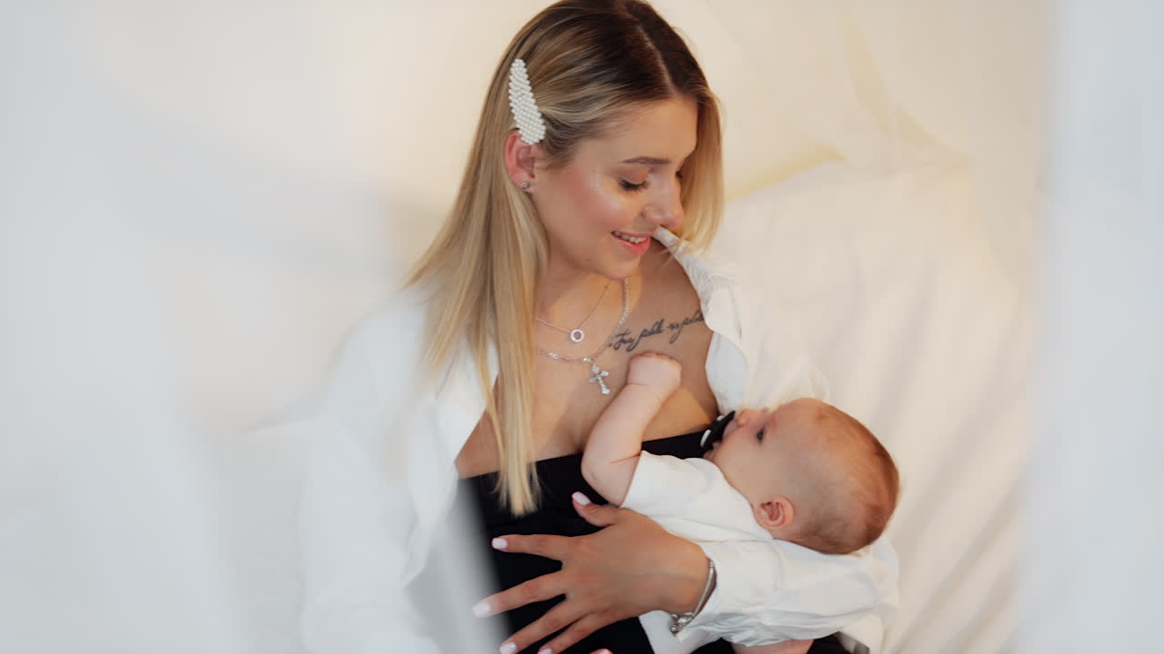 Beautiful blonde woman waving her newborn child. Happy mother with her beloved baby.