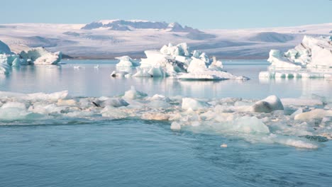 icebergs and ice floes in arctic sea lagoon in mountainous landscape