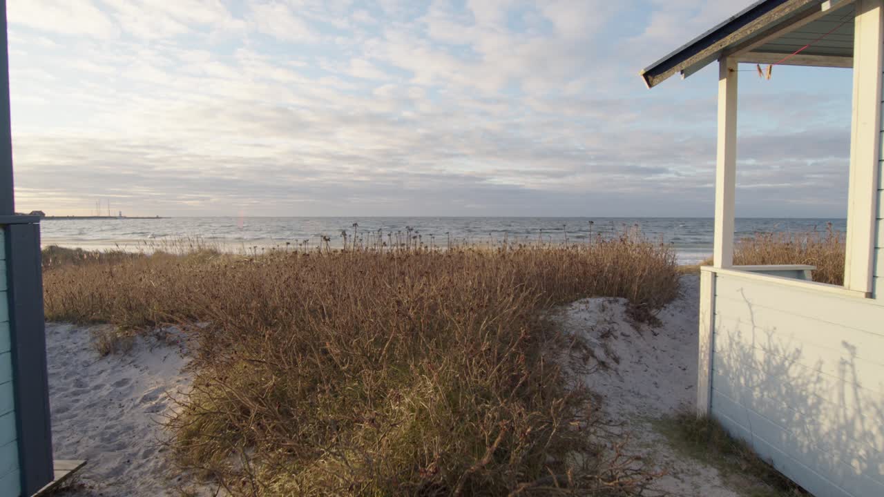 el movimiento de la cámara deslizándose hacia adelante junto a las cabinas de baño de la playa revela una playa oceánica épica