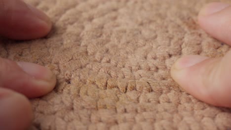 close-up of hands gently touching a brown cotton surface, highlighting texture and detail