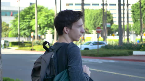 a young caucasian man traveling alone standing outside of a los angeles train station waiting for his ride to arrive