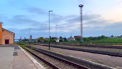 paisaje industrial con torre de luz, vías de tren y una plataforma temprano en la mañana