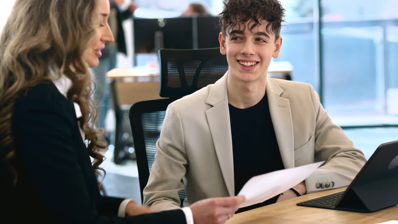 Female team leader discussing business affairs with a young worker using charts. Business meeting at the office. Papers and tablet on the table
