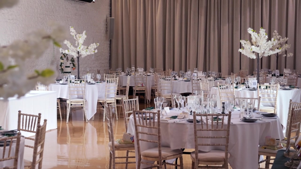 Presentación elegante de pastel de bodas en un salón de recepción decorado con flores y mesas.