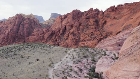 Tiny-man-walking-up-a-path-in-rocky-landscape-in-Red-Rock-Canyon-National-Conservation-Area-in-Nevada,-USA-in-slow-motion