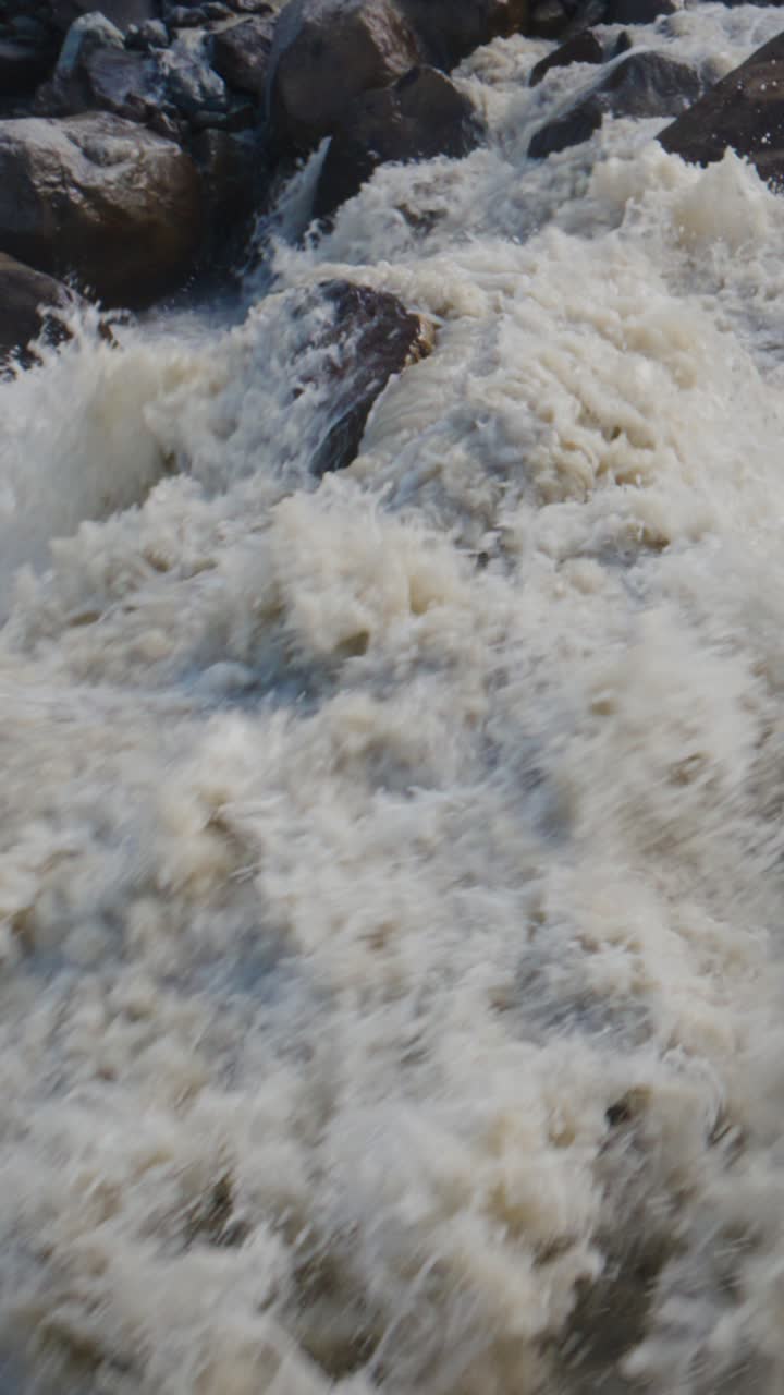 Acqua di fiume torbida e turbolenta che scorre impetuosa sulle rocce