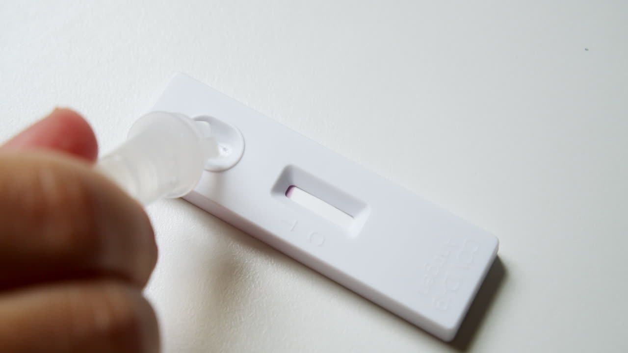 Close-up of an individual's hand while testing for possible COVID-19 infection, using an Antigen Test Kit