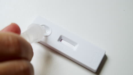 close-up of an individual's hand while testing for possible covid-19 infection, using an antigen test kit