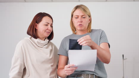 tailor and colleague engaging in cheerful conversation while reviewing fabric samples together, exchanging ideas and discussing material selections during collaborative design session