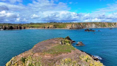 Drones-Volando-Sobre-Una-Pequeña-Isla-Con-Aves-Marinas-Anidando-Con-Mares-Azul-Oscuro-Y-Cielos-Espectaculares-En-Waterford,-Irlanda,-Estableciendo-Fotografías-De-Paisajes