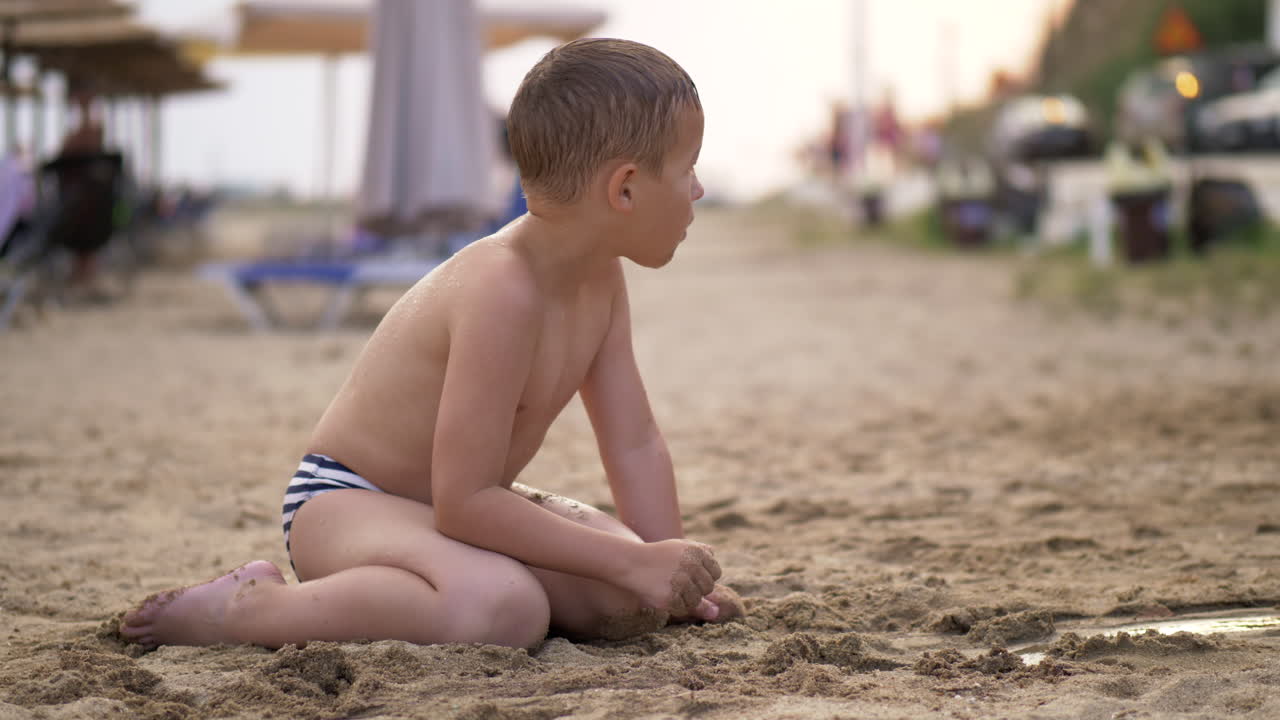 Kid playing with sand the at beach during summer vacation